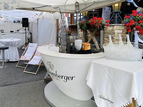 An outdoor tent with an elegant reception desk and floral arrangements. The area appears to be prepared for an event or celebration.