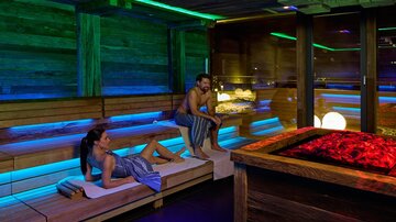 A relaxing wellness area with gentle lighting effects. A woman and a man are enjoying the calming atmosphere in a sauna.