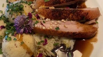 A delicious dish with fried meat, garnished with herbs and edible flowers. Served with a side of potatoes and sauce.