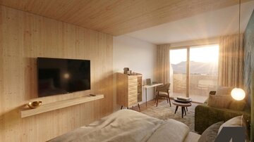A modern room with wooden paneling and large windows. The space is bright and inviting, with a television, a desk, and a cozy seating area.