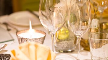 An elegantly set table with glasses and a candlelight. The napkin is artfully folded and creates a festive atmosphere.